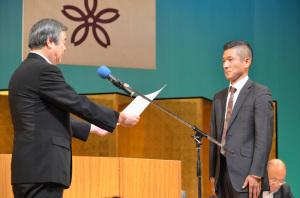 市長から笑い飯哲夫さんに広報大使委嘱状を手渡ししている様子