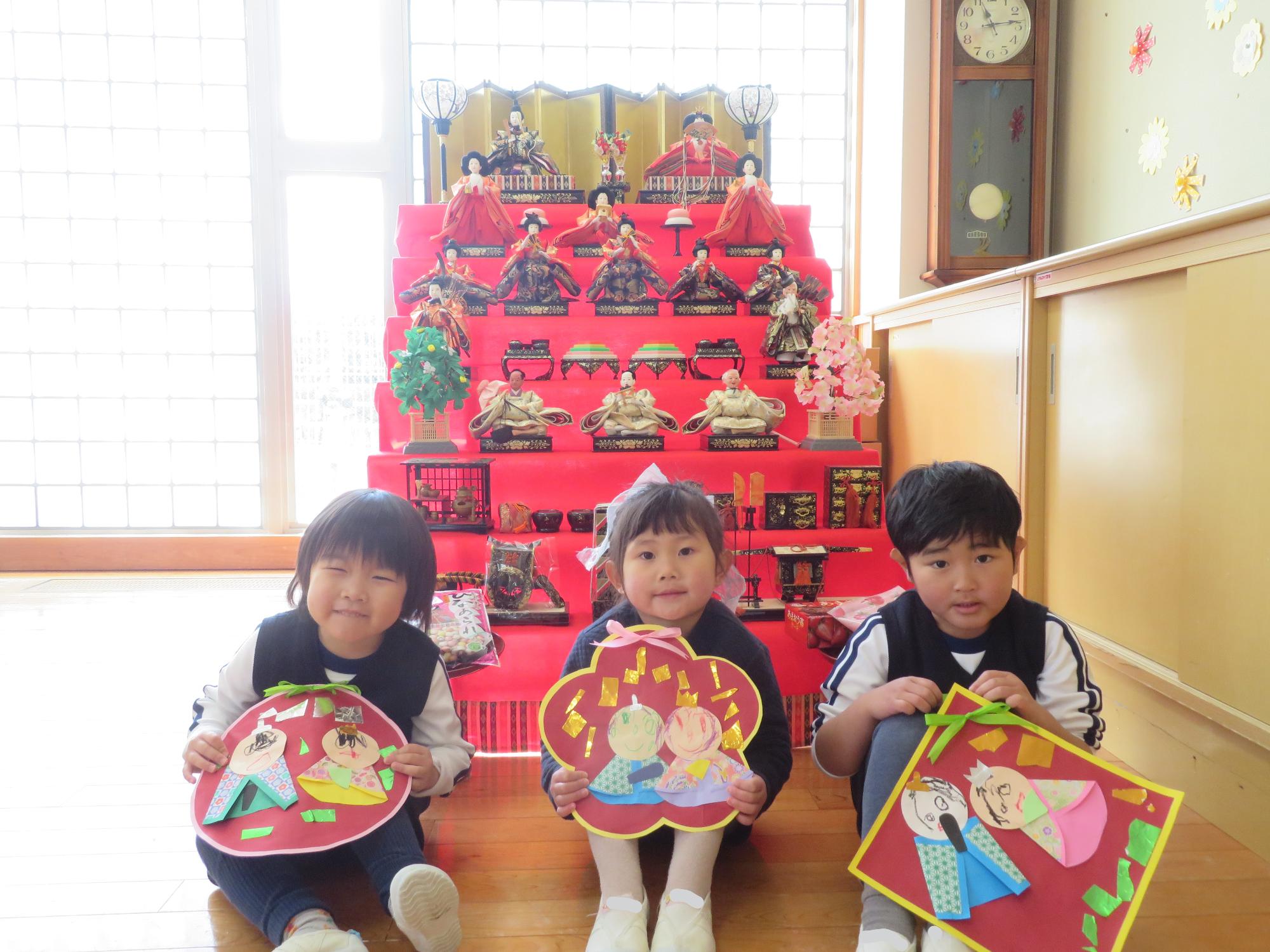 年少児がお雛様の前で写真を撮っているところ。