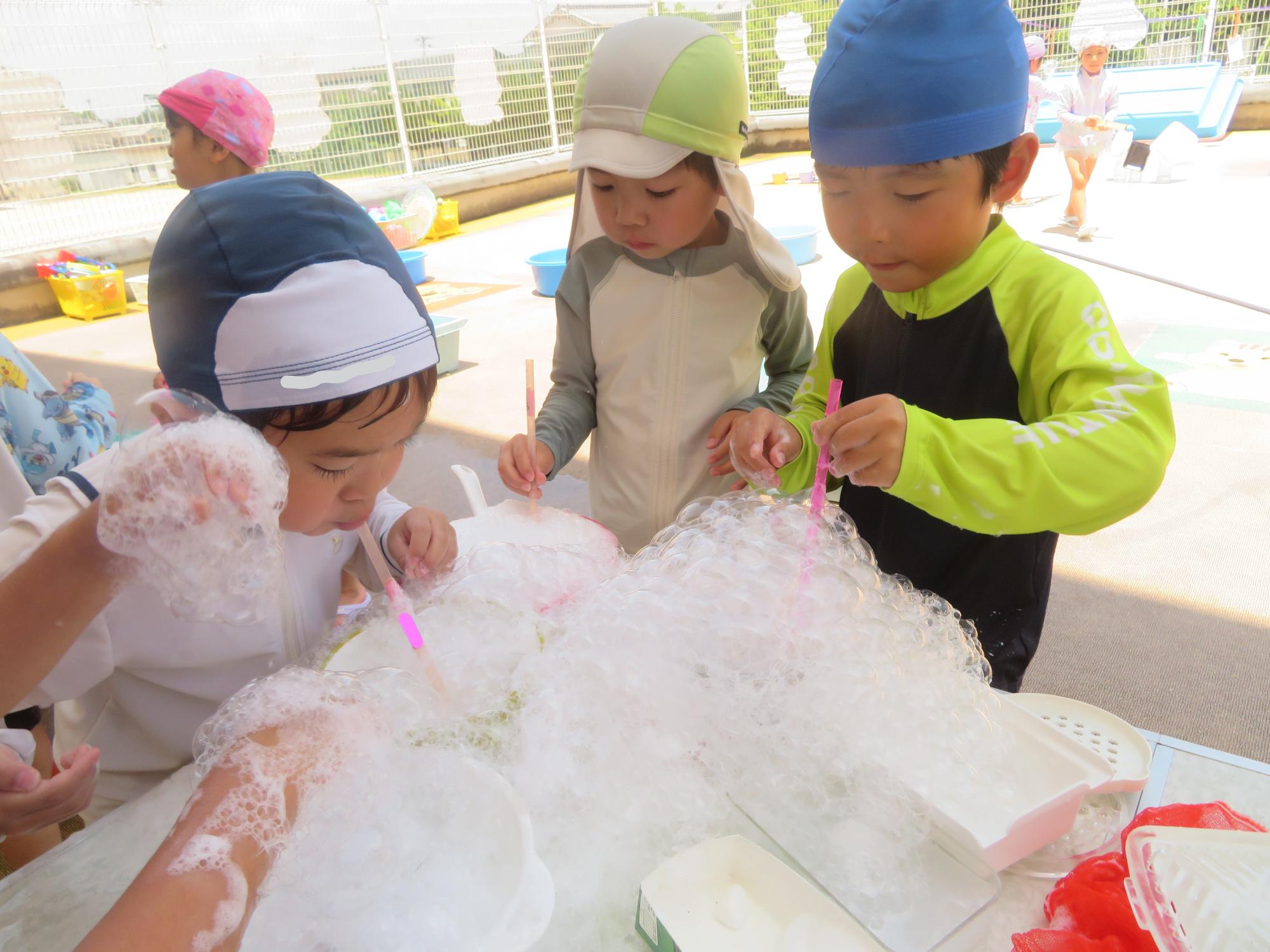 ストローで泡をブクブクと吹いている子どもたち
