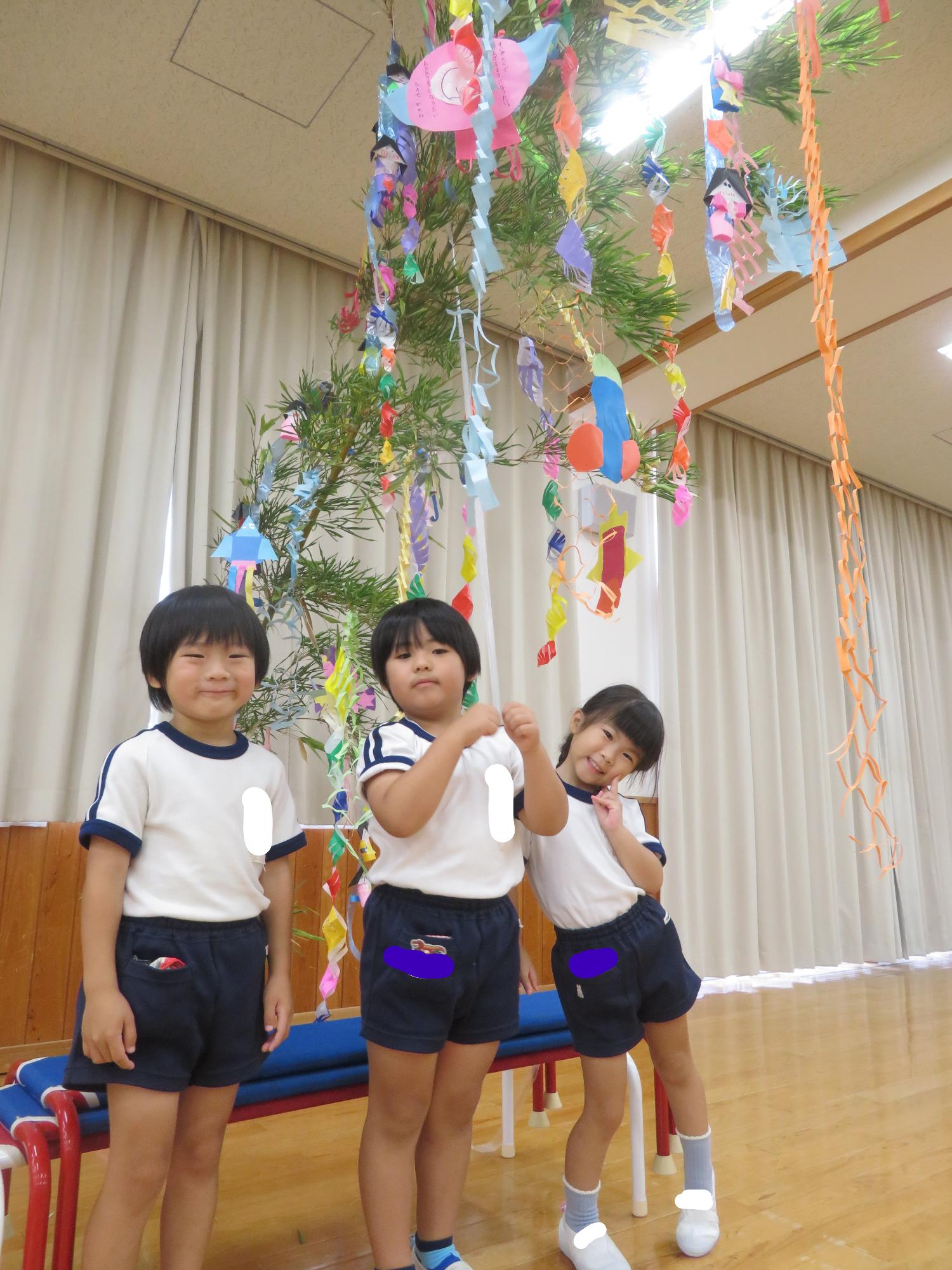 幼児が笹飾りの前で写真を撮っている。