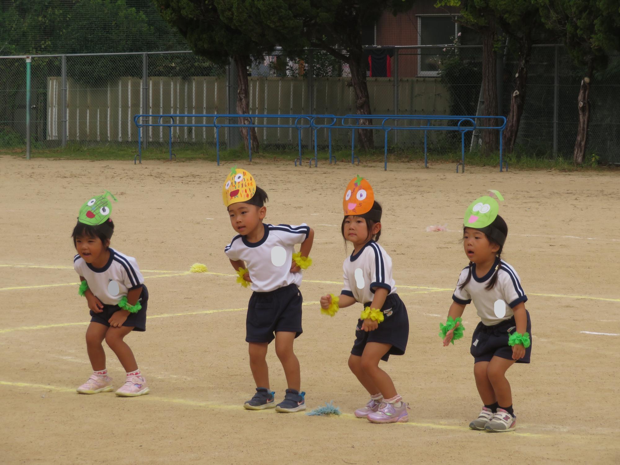 年少児がフルーツのお面をつけてダンスをしている。