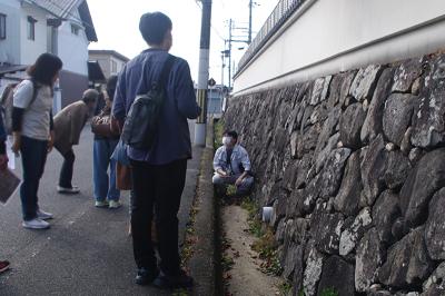 芝村陣屋の跡地に残る石垣について語る研究員と聴き入る参加者のようす