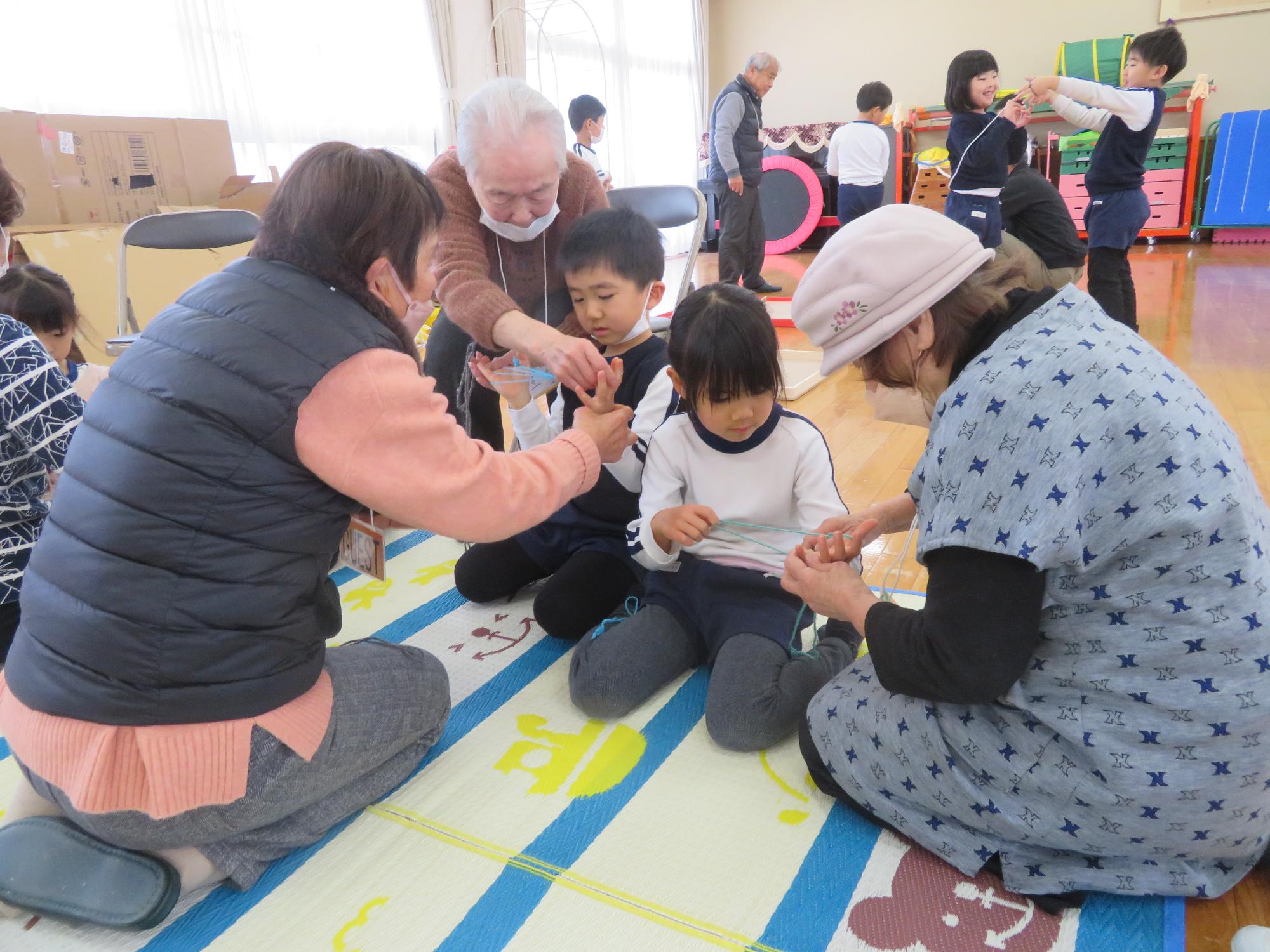 老人会の方にあやとりを教えてもらっているところ