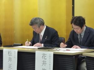 協定書に署名する松井市長（左）と花井機構長（右）